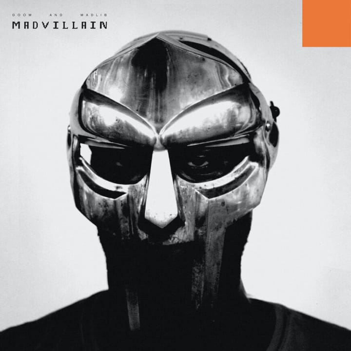 A photo of MF DOOM wearing his signature Gladiator mask. The photo is black and white and very saturated.